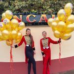 Zwei Messehostessen mit vielen goldenen Luftballons